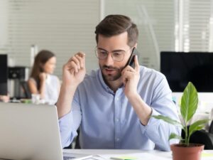 Sales manager consulting client talking on phone in office.