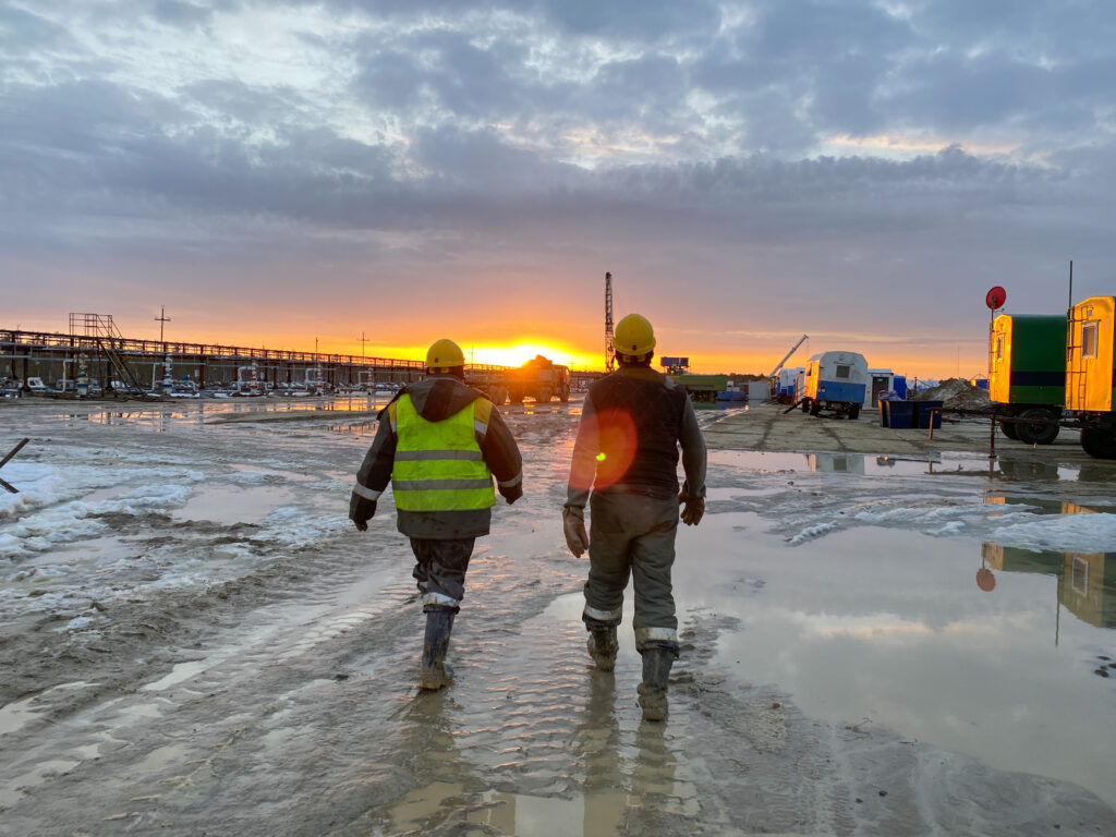 Two workers walking within an oil rig site
